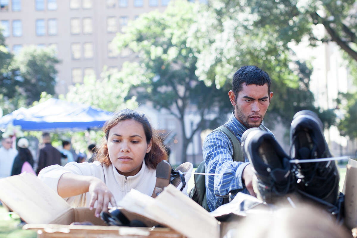 (From left) Anastasia Barrera and Erick Osorio look through boxes filled with shoes November 1, 2014 during Calvary Chapel of San Antonio 17th annual Joy of Jesus Outreach at Travis Park. The congregation provided more than twenty services for the community including free hair cuts, manicures, and massages.