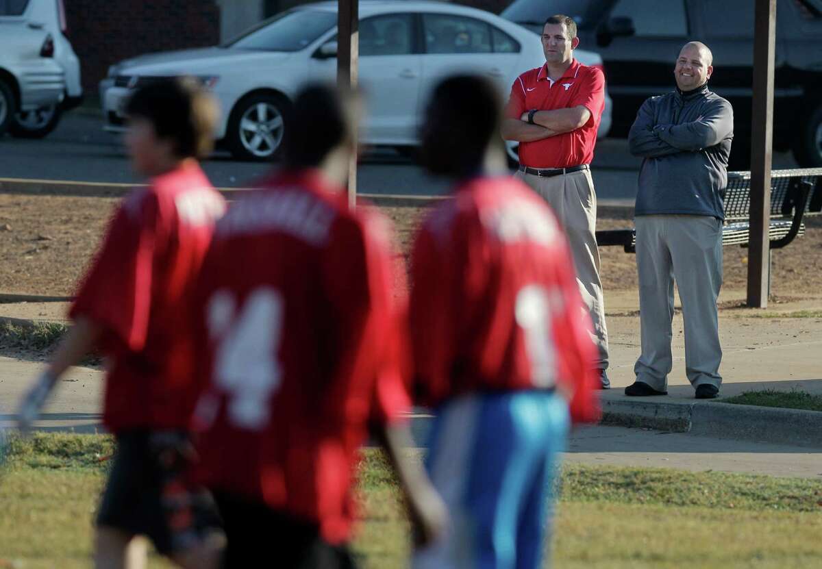Clint Harper, left, Marshall High School head football coach, watches a touch football game during physical education class. Harper thinks touch football helps develop a variety of skills needed in tackle football.﻿