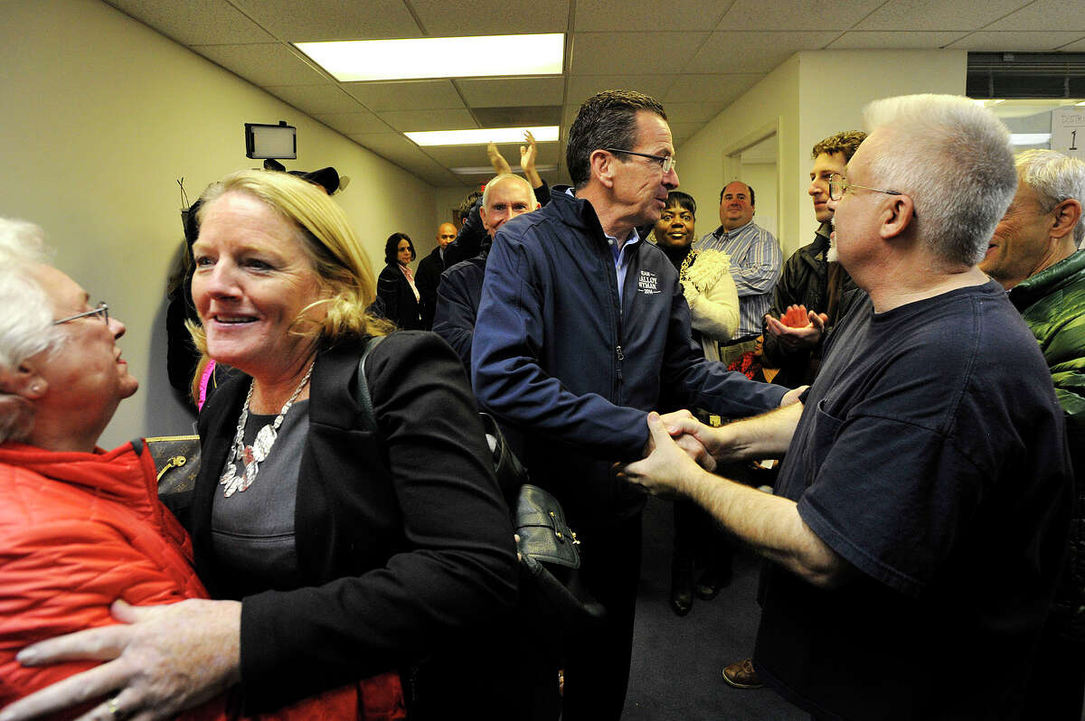 Gov. Dannel P. Malloy greets people as he and his wife, Cathy, enters the room before addressing a crowd of Democratic supporters at Stamford Democratic Headquarters in Stamford, Conn., the evening before polls open in the state on Monday, Nov. 3, 2014.