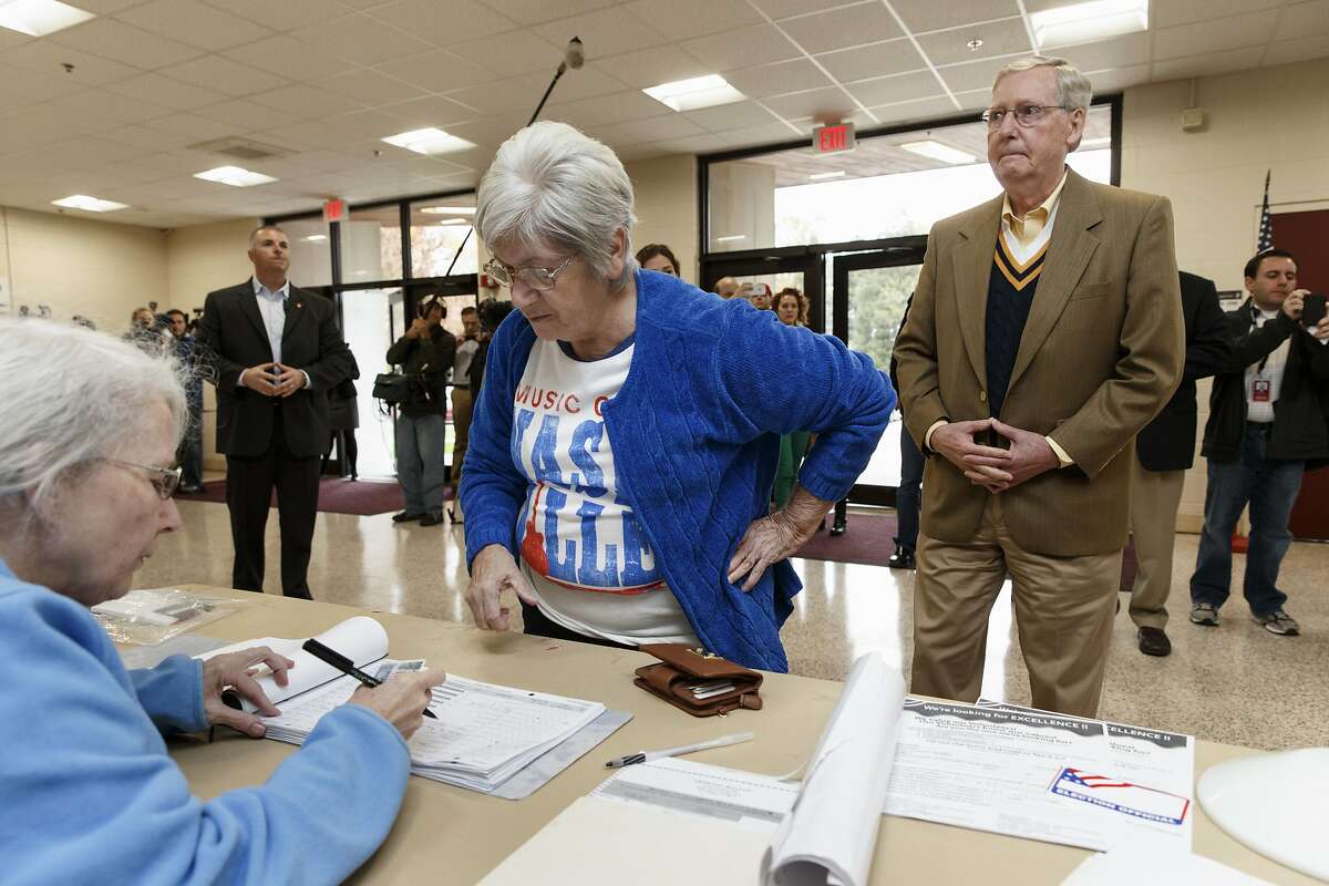 Senate Minority Leader Mitch McConnell of Ky., right, waits in line to check in to vote in the midterm election at the voting precinct at Bellarmine University in Louisville, Ky., Tuesday, Nov. 4, 2014. The Kentucky Senate race, with McConnell, a 30-year incumbent, facing a spirited challenge from Democrat Alison Lundergan Grimes, has been among the most combative and closely watched contests that could shift the balance of power in Congress. 