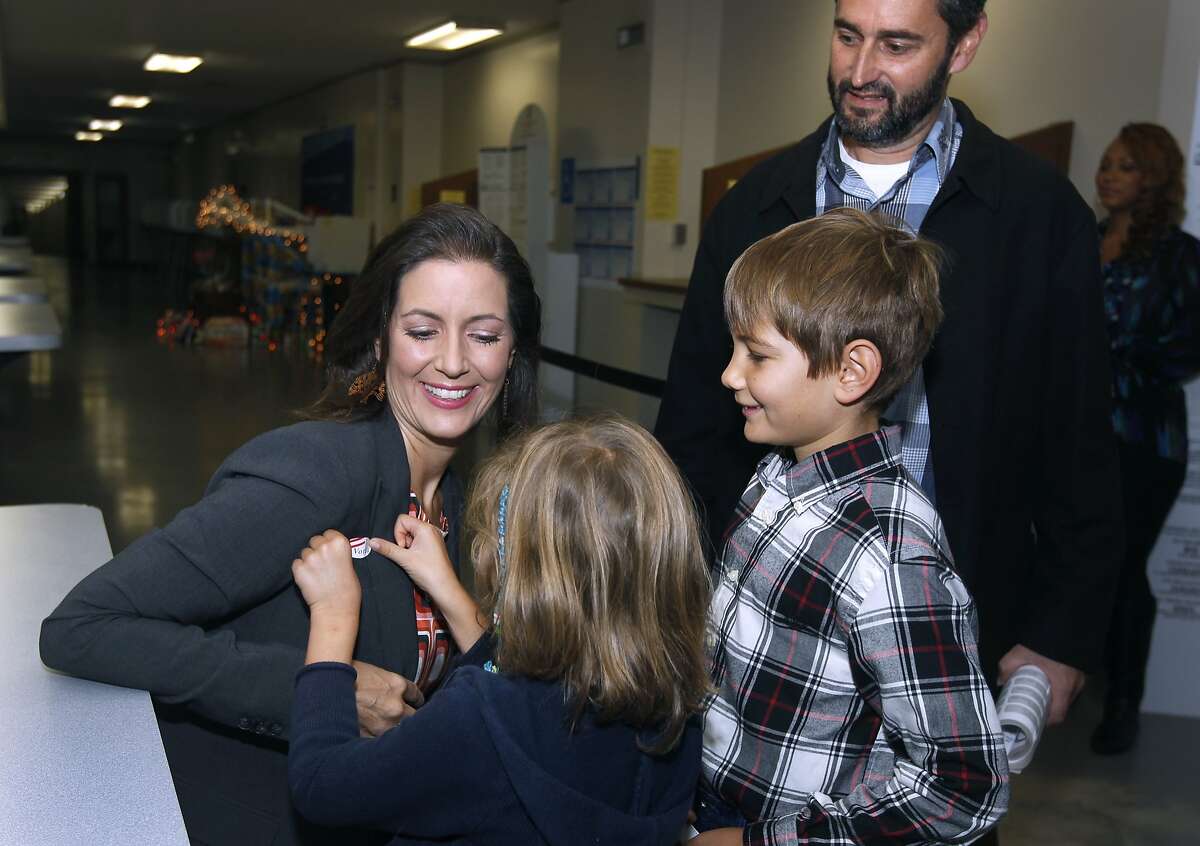 Lena Fahey, 7, applies a voter sticker to her mother, Oakland mayoral candidate Libby Schaaf, who dropped off her absentee ballot to the Alameda County Registrar of Voters office with son Dominic, 11, and husband Sal Fahey in Oakland, Calif. on Tuesday, Nov. 4, 2014.
