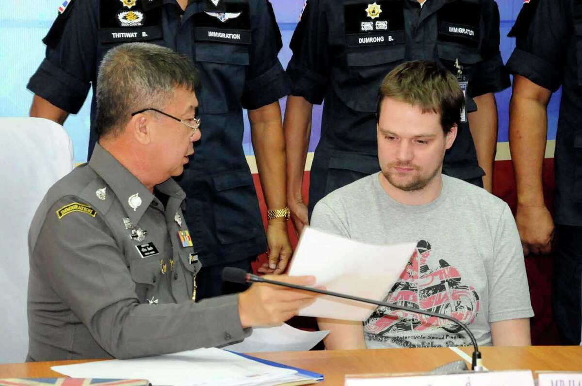 A Thai immigration officer, left, shows a paper document to Swedish Hans Fredrik Lennart Neij at Immigration office in Nong Khai province, Thailand, Tuesday, Nov. 4, 2014. Neij, one of the founders of popular file-sharing website The Pirate Bay, has been arrested under an Interpol warrant as he was crossing into Thailand from Laos, police said Tuesday. (AP Photo) THAILAND OUT