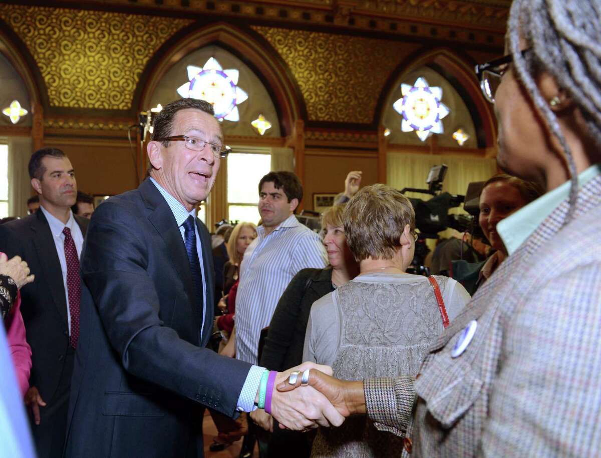 Gov. Dannel P. Malloy shakes hands with supporter Almena Thompson, of the Service Employees International Union District 1199, Wednesday, Nov. 5, 2014, during a news conference at the State Capitol in Hartford, Conn.