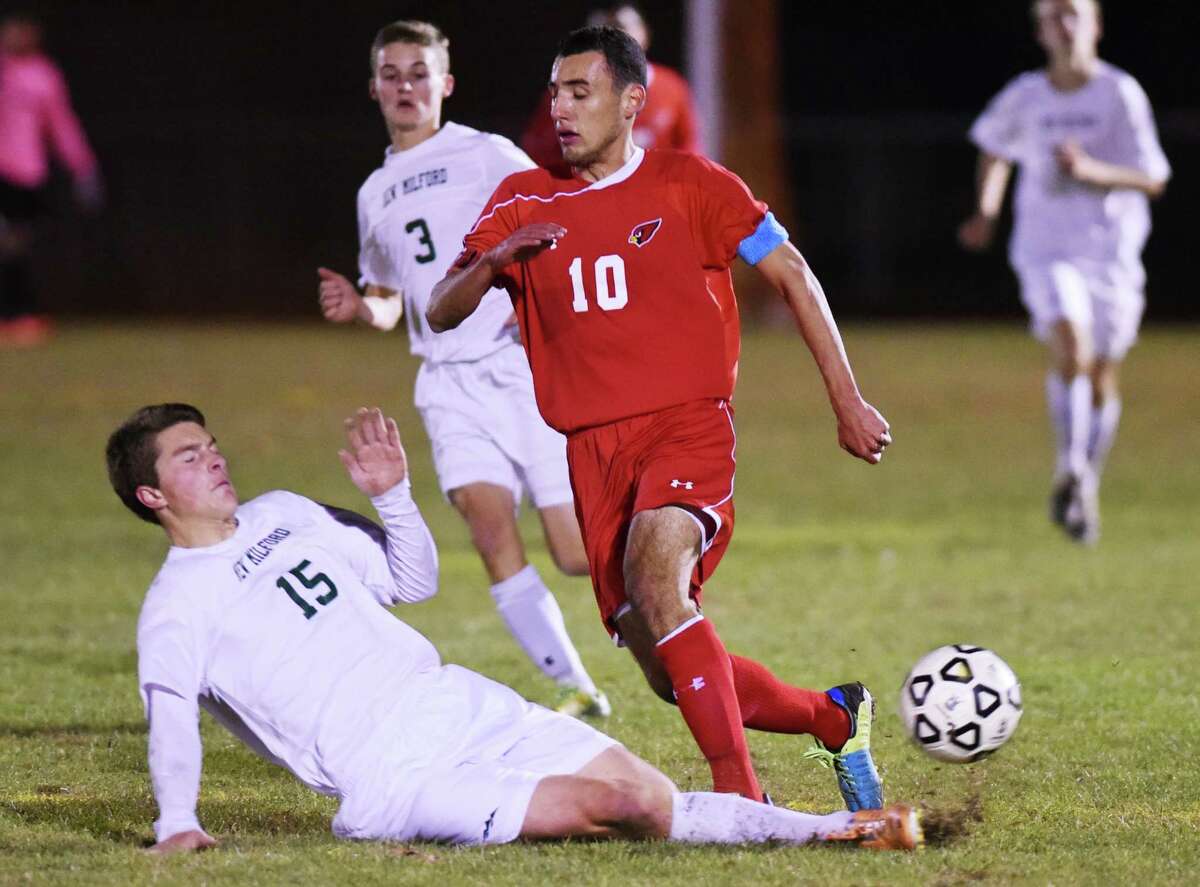 New Milford's Spencer Ranno slide tackles the ball from Greenwich's Paul Quiroga in Greenwich's 3-1 win over New Milford in the CIAC Class LL boys soccer second round game at New Milford High School in New Milford, Conn. Wednesday, Nov. 5, 2014.
