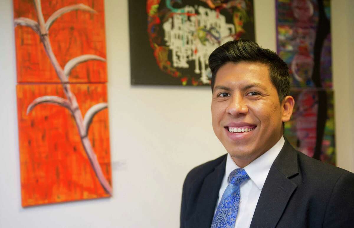 Rene Soto poses for a photo in his Stamford office as his artwork, and artwork by artists he promotes, hangs behind him on Thursday, November 6, 2014.