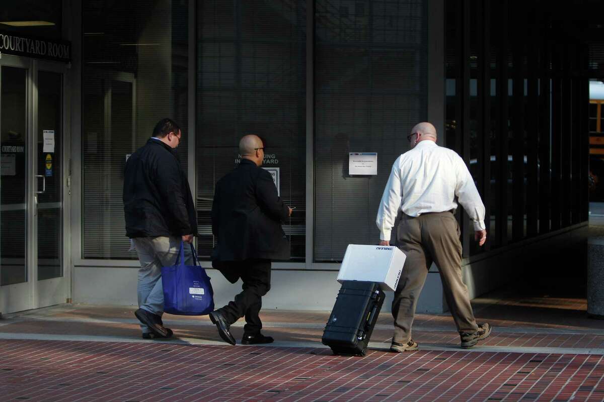 Representatives with the California Attorney General's office carry a bag and rolling case with a box as they leave the California Public Utilities Commission offices on Thursday, November 6, 2014 in San Francisco, Calif.