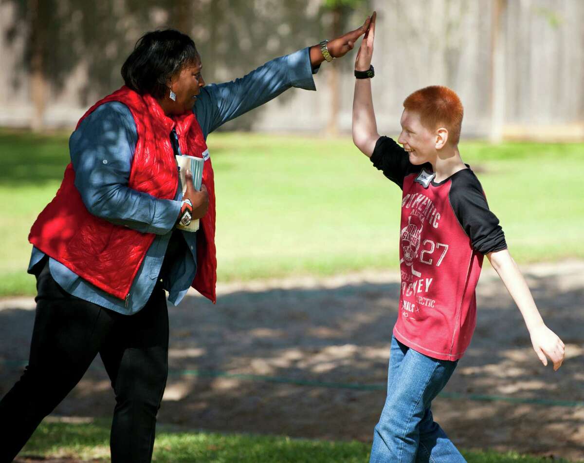Matthew, 12, high fives Daphne McCadney with Texas Child Protective Services at an adoption festival sponsored by the Pearland Rotary on Saturday, Nov. 8, 2014 at the Silverlake Clubhouse in Pearland, Texas. Matthew and about 19 other children available for adoption were at the event along with prospective adoptive parents.
