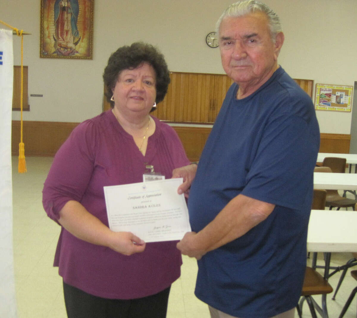 Sandra Aviles, the benefits counselor with the Bexar Area Agency on Aging, receives a certificate from veteran Abel Hernandez, a longtime member of the National Active and Retired Federal Employees association.