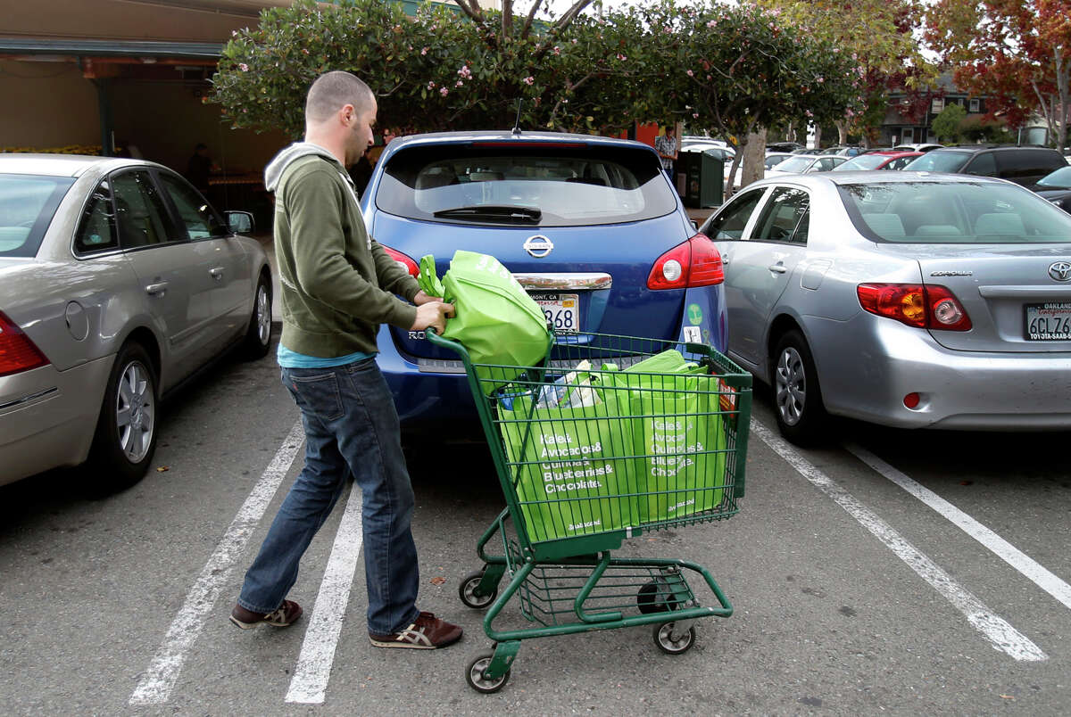 Yonatan Schkolnik brings groceries to his car in the parking lot of Whole Foods for his Instacart delivery.