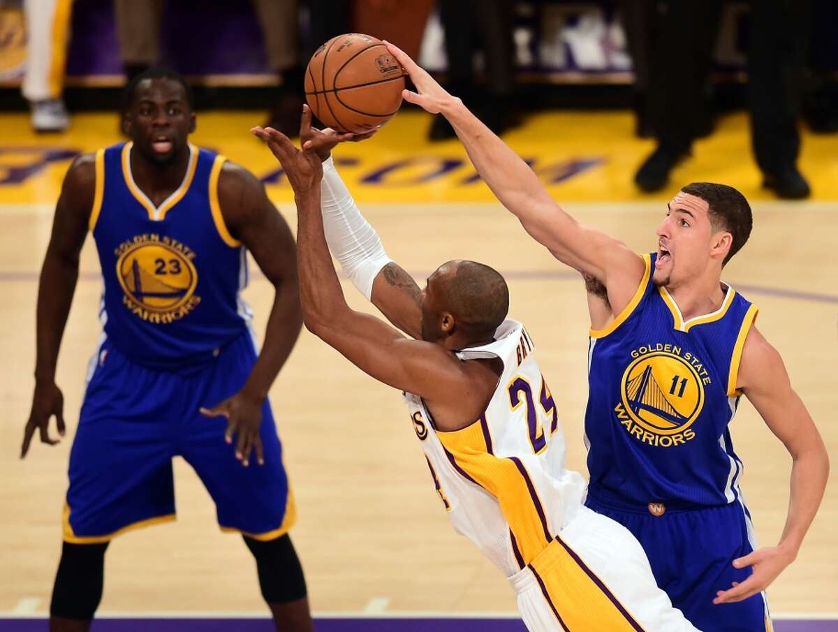 The Lakers’ Kobe Bryant attempts a shot as the Warriors’ Klay Thompson goes for the block and Draymond Green looks on.