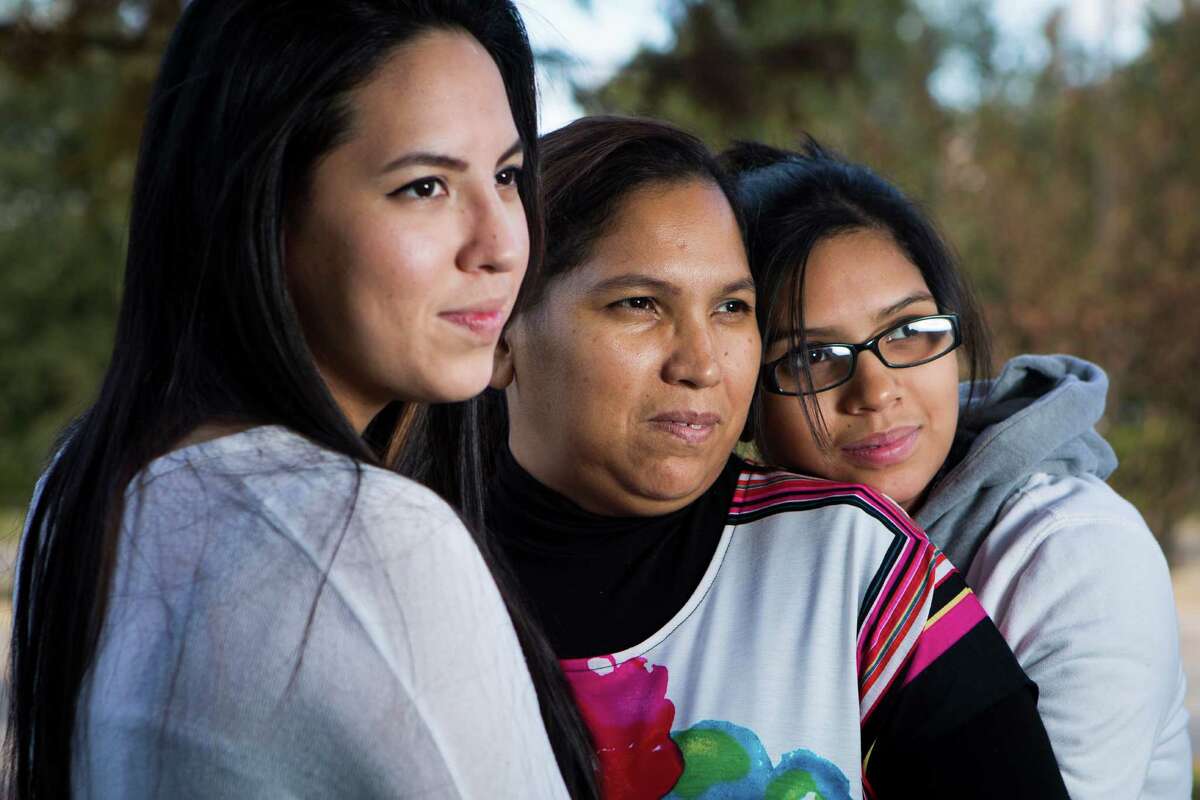Maria Espinoza, center, is embraced by her daughters Glenda Moreno, left, and Wendy Moreno, both U.S. citizens. Espinoza, who crossed the border years ago, said she hopes the president will bring good news. ￼￼