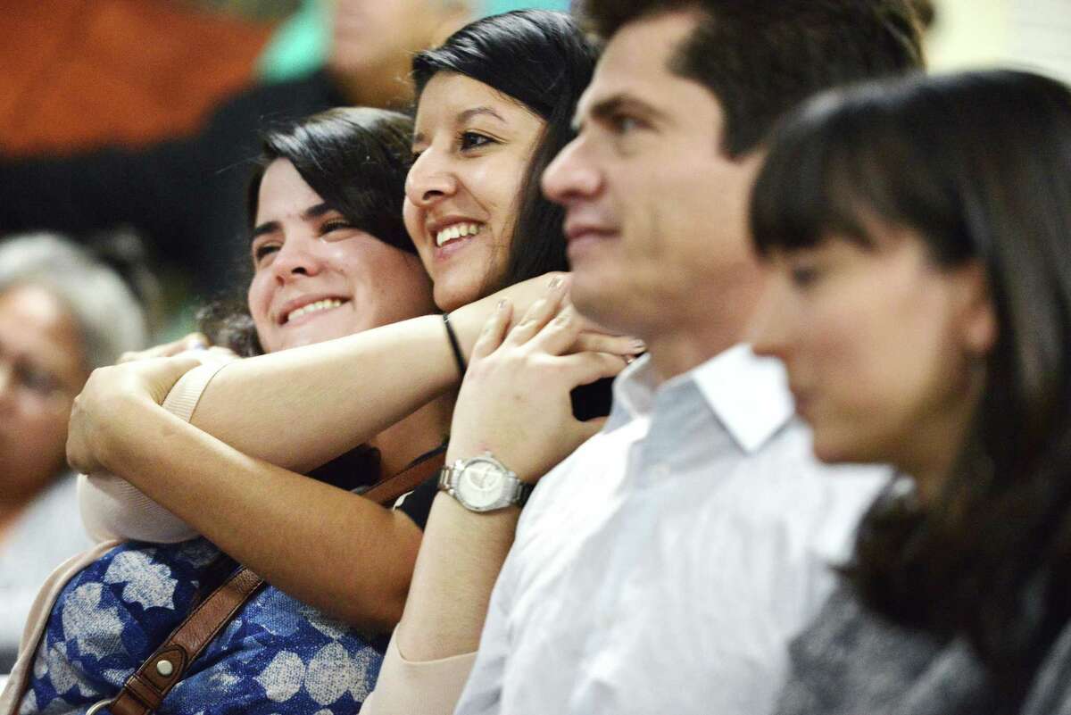 Anabel Martinez, left, hugs Maria Calixto, second left, after hearing the news that certain undocumented immigrants will be able to apply for work permits via President Obama's executive action, while she and other community members attended a watch party at the Divine Redeemer Presbyterian Church on Thursday, November 20, 2014. Martinez and Calixto, both citizens, are members of St. Mary's Center for Legal and Social Justice, and say that they were naming off the names of friends and clients who were going to benefit from this most recent action on immigration.