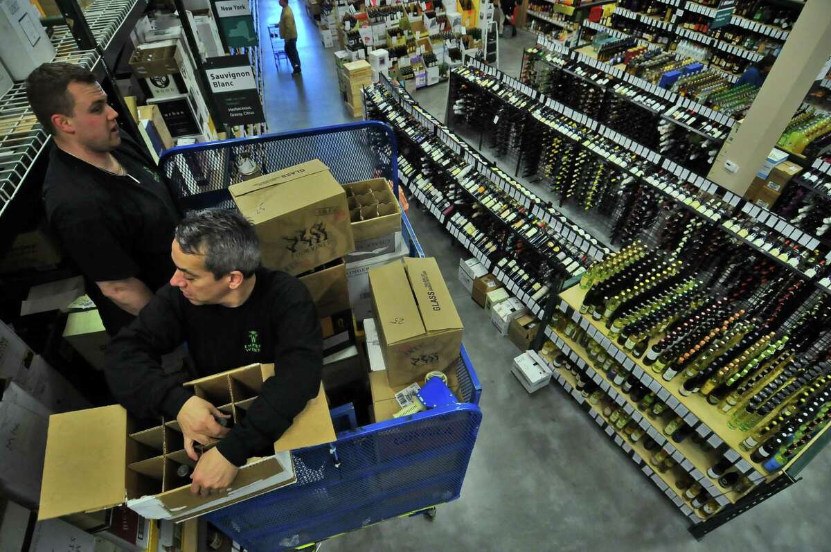 Empire Wine & Liquor Outlet employees Rich Smith, left, and Mike Witt, right, stand atop a lift as work on restocking wine in Colonie, NY on Tuesday April 13, 2010. For story about proposed liquor license legislation. (Philip Kamrass / Times Union)