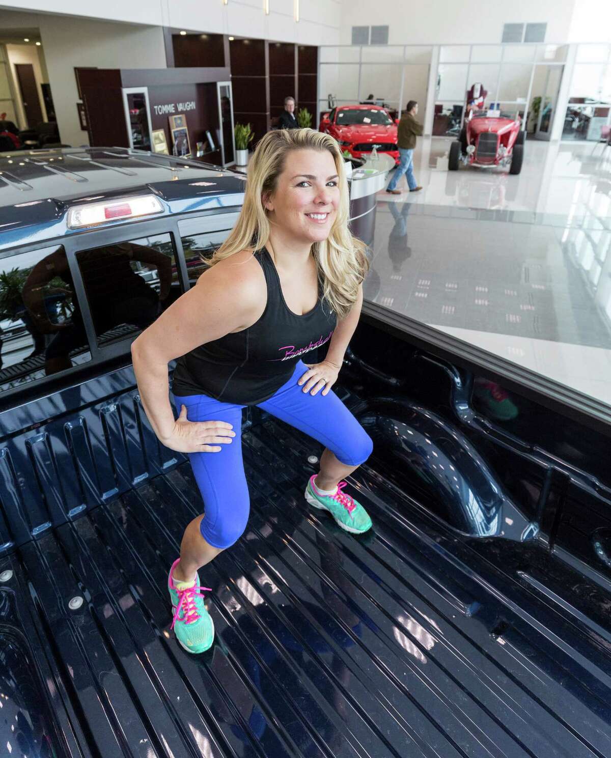 Cari Shoemate demonstrates her new workout regime on a Ford pickup inside the showroom of Tommie Vaughn Ford, 1201 N. Shepherd Drive. ID: Shoemate demonstrates squats in the bed of the truck. Friday November 4, 2014 (Craig H. Hartley/For the Chronicle)