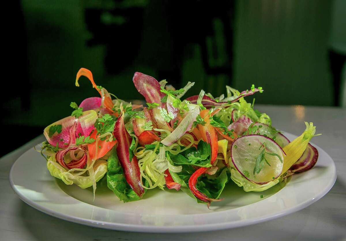 The Little Gem salad’s cold greens are accented with smashed avocado, shaved carrots, watermelon radishes, and whole leaves of parsley and other herbs in a citrus vinaigrette.