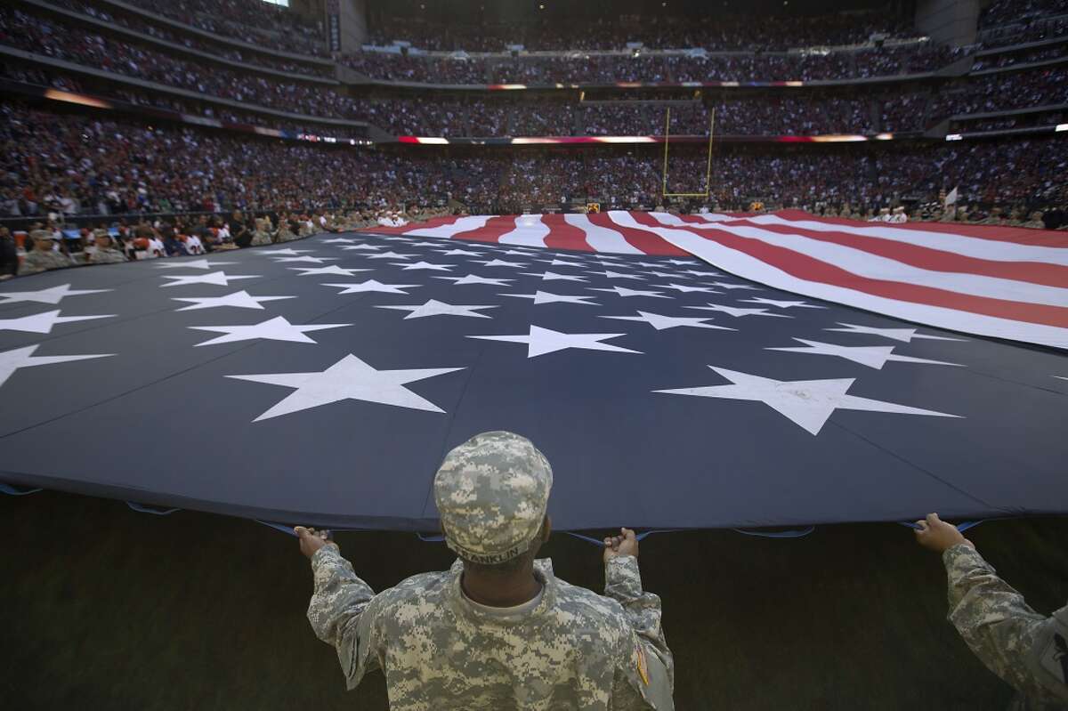 Service members hold the American flag during the national anthem before an NFL football game between the Houston Texans and the Cincinnati Bengals at NRG Stadium on Sunday, Nov. 23, 2014, in Houston. ( Brett Coomer / Houston Chronicle )