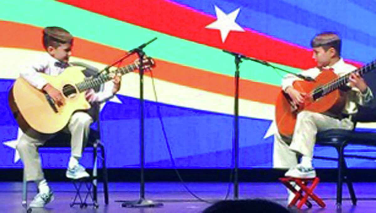 Alex Kalamikov, 5, and his brother, Ivan, 7, now residents of New Milford, perform on guitar in June 2014 at Radio City Music Hall in New York City. Courtesy of the Kalamikov family