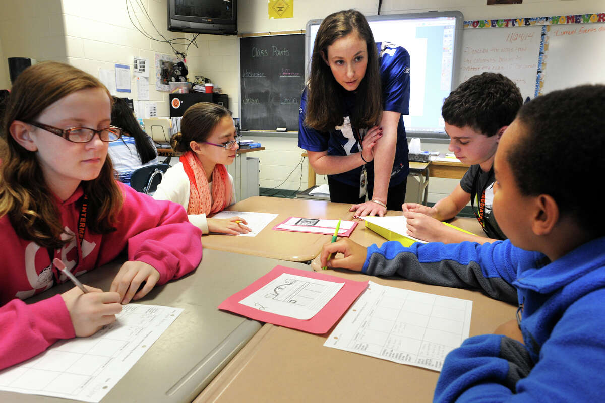 Jordanna Borska leads a lesson with her 7th grade social studies class at Shelton Intermediate School, in Shelton, Conn. Nov. 24, 2014. This day's lesson was an investigation into American colonists protest to the British Stamp Act of 1765. Borska is seen here with, from left, students Kayla Krasonski, Megan Rudko, Chris Belden and Nasir Jones.
