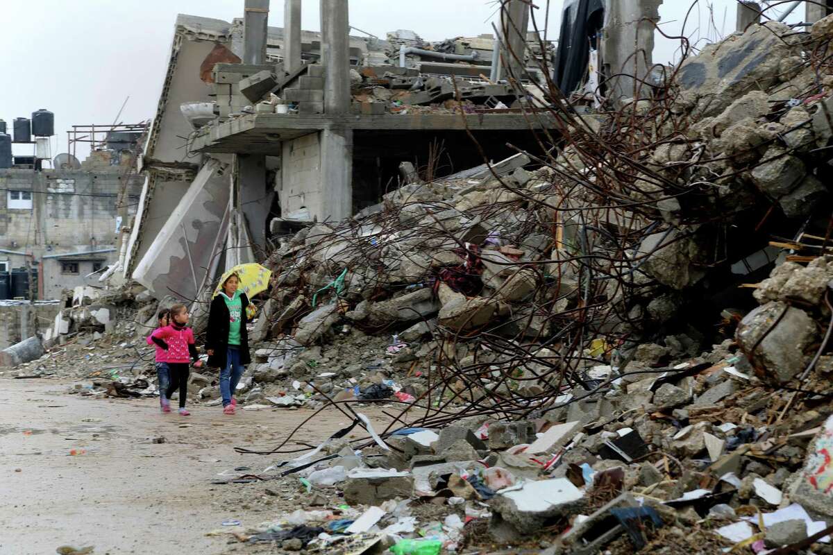 Palestinian girls walk past destroyed homes from recent conflict between Israel and Hamas in Shijaiyah, neighborhood in Gaza City, Monday, Nov. 24, 2014.