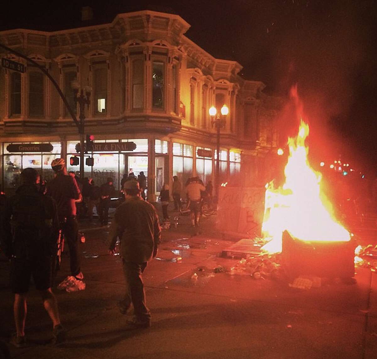 A fire burns in the middle of the street in front of a building being looted by protesters in downtown Oakland early on Tuesday, Nov. 25, 2014. 