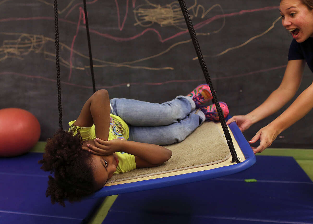 Brittany Morgan, right, ABA Therapist, works with a client at the Autism Treatment Center, Thursday, Nov. 6, 2014. The swing was part of the child?•s reward after a lesson. Autism Treatment Center is San Antonio's first, and only provider of autism services that meet the needs of individuals at every stage of life. Founded in 1976, the agency has grown with the expanding needs of the San Antonio children, families and adults who have struggled to understand and overcome the challenges autism presents. There are 75 employees and a $5 million budget to provide services including early diagnosis and therapy for children, a special TEA certified school, adult vocational training, and residential homes.