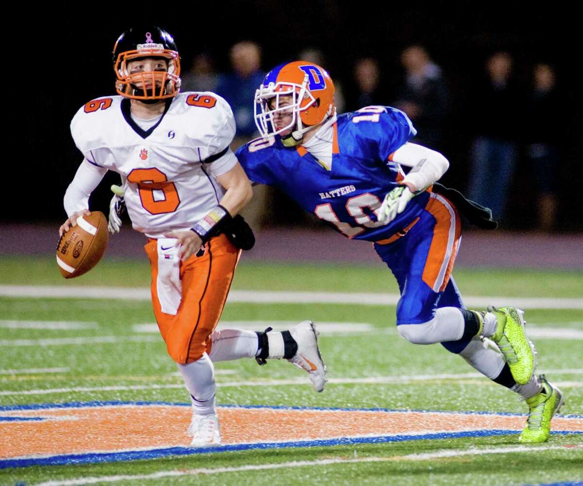 Ridgefield High School quarterback Ryan Dunn is pursued by Danbury High School's Connor Firmender during a game played at Danbury. Tuesday, Nov. 25, 2014