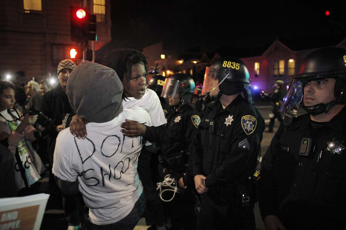 Tina and her son Pharoah, walk up near the line of police at Jackson Street and 6th Street where protesters tried to get to the on ramp to highway 880 during local protests about Ferguson Police shooting of Michael Brown on Tuesday, November 25, 2014, in Oakland, Calif.