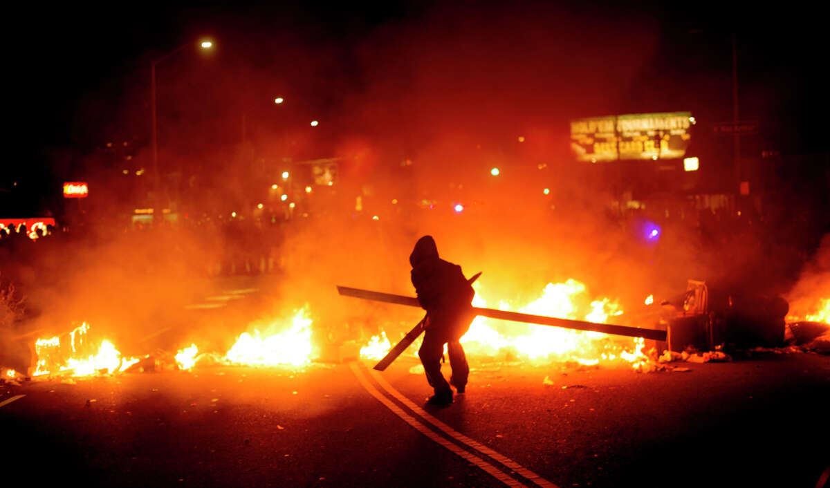 A protester adds wood to a fire burning in Oakland on Tuesday night.