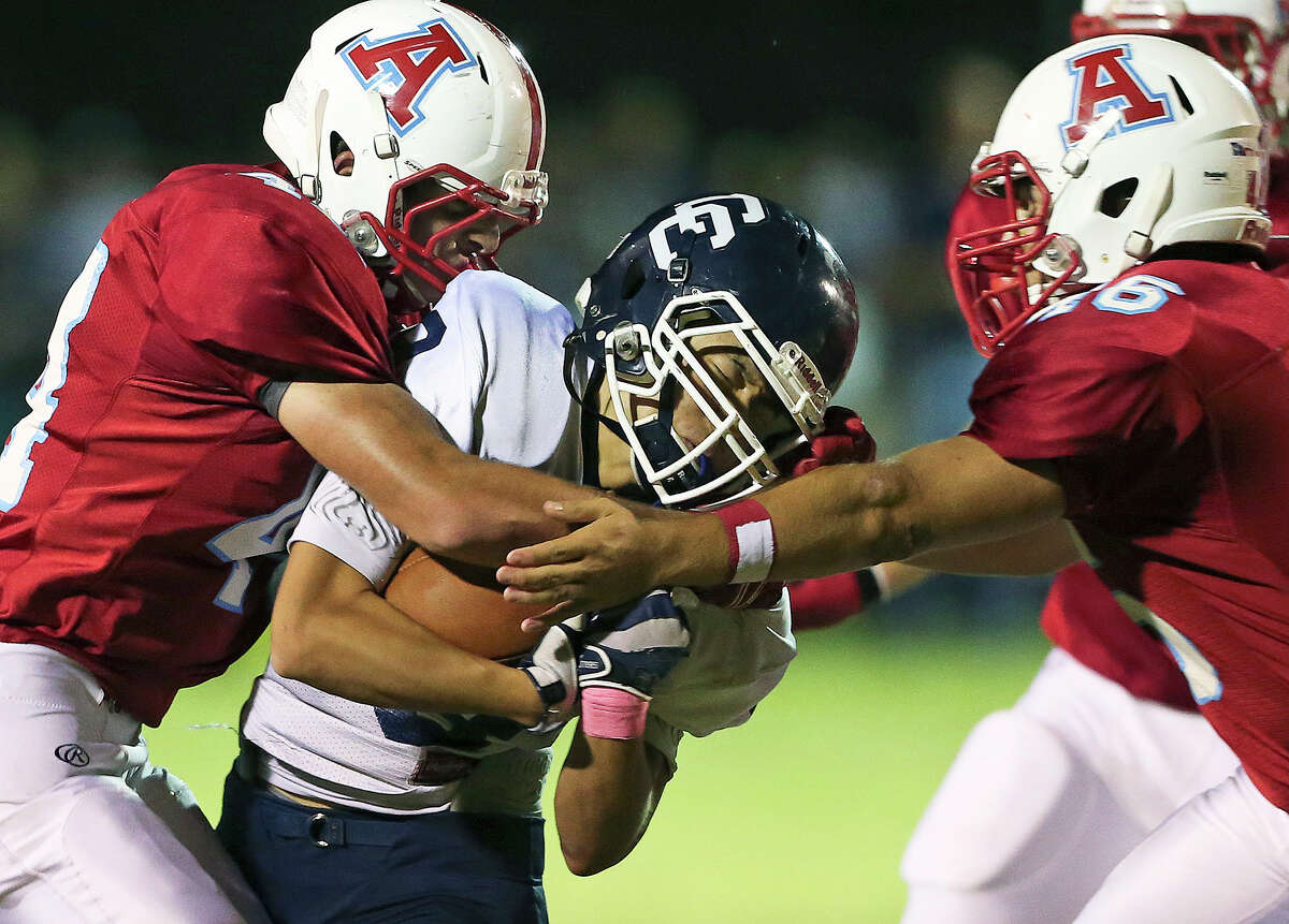 Button quarterback Jimin Suh gets caught between Apache tacklers Steven Wynn (left) and Kyle Cantu as Antonian hosted Central Catholic at Ferrara Stadium on October 17, 2014.