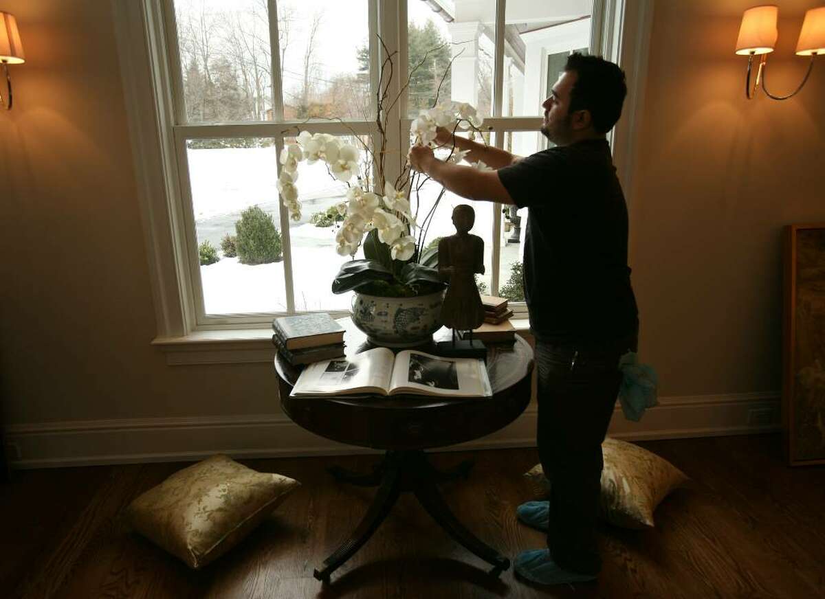 Designer Andres Galvan of Meridith Bare and Associates from Los Angeles, CA prepares a flower arrangement in the living room of 31 Woody Lane in Westport.