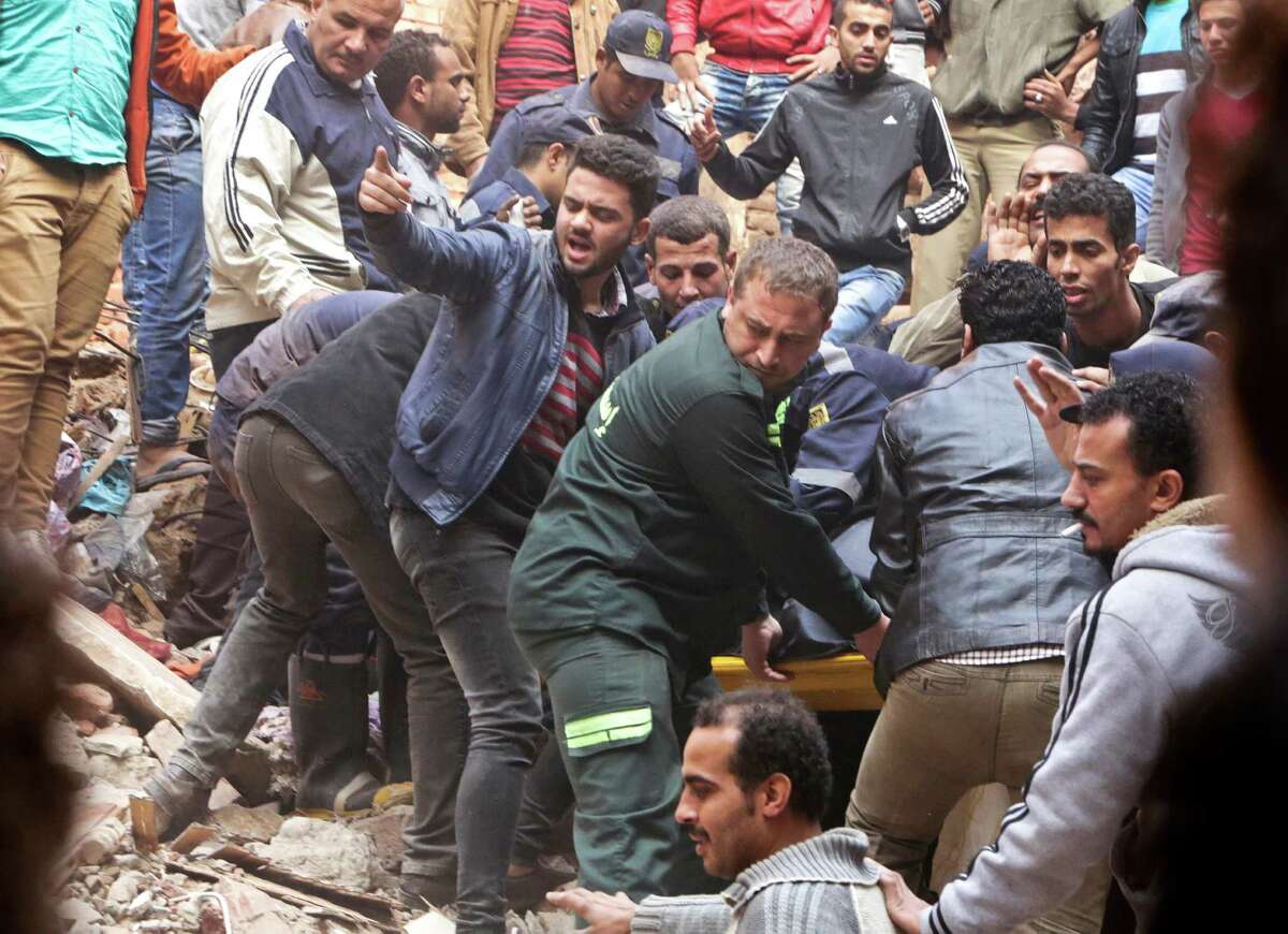 Egyptian volunteers and rescuers carry the body of a victim in the rubble of a building that collapsed in the Cairo suburb of Matariya, early Tuesday, Nov. 25, 2014. Police officials say several people were killed. Building collapses are common in Egypt, where shoddy construction is widespread in shantytowns, poor city neighbourhoods and rural areas.