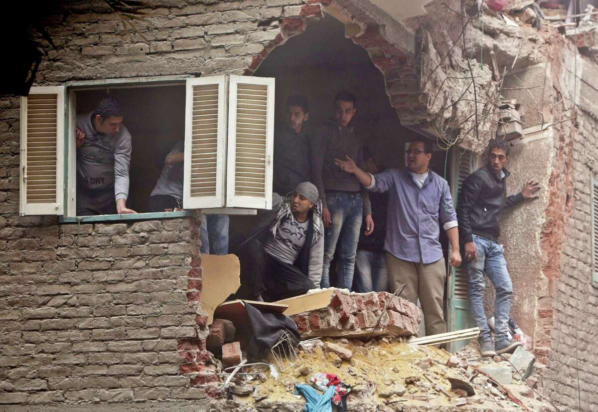 Neighbors watch rescue operation from their damage balcony in front of a building that collapsed in the Cairo suburb of Matariya, early Tuesday, Nov. 25, 2014. Police officials say several people were killed. Building collapses are common in Egypt, where shoddy construction is widespread in shantytowns, poor city neighborhoods and rural areas.