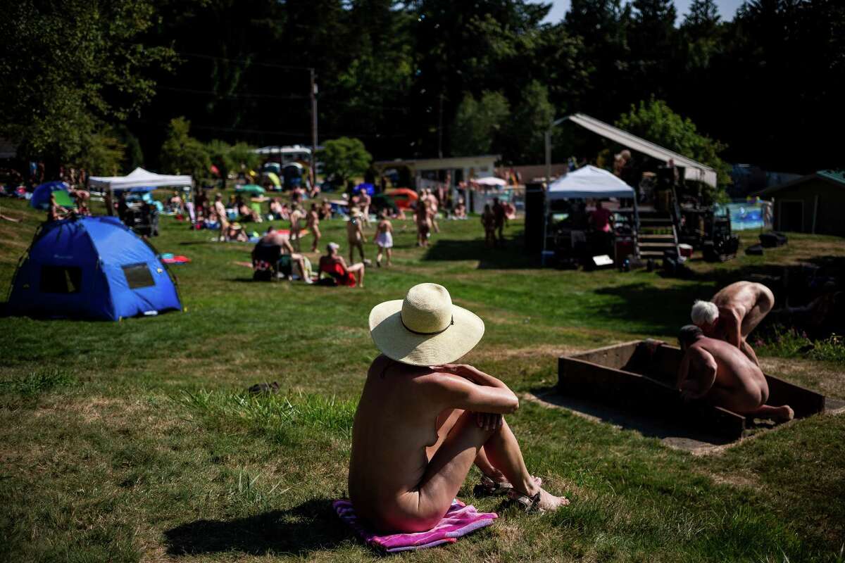 Seattlepi.com staff photographer Jordan Stead spent 2014's summer and fall months documenting the often-misunderstood culture behind nudism at Issaquah's Fraternity Snoqualmie family nudist park. Expand arrow in lower right is recommended for better viewing. Editors note: This photo story includes partial front and back nudity, both female and male. Names have been removed and all subjects agreed to be photographed. And yes, the photographer was also nude. Nestled on a side of Tiger Mountain near Issaquah, a significant slice of history goes largely unnoticed by passers-by on the highway less than a mile below. The truth: Since 1945, thousands have enjoyed nature in nothing but their birthday suits on 40 acres of Fraternity Snoqualmie's family nudist park, a 501(c)(7) nonprofit. Nudism -- also known as "naturism" -- is often misunderstood. A strict set of rules -- "do's" and definite "don'ts" -- has long been set in place, ensuring safety among park attendees. In this photo, park-goers don sun hats and sunscreen to take in the sights and sounds of Fraternity Snoqualmie's annual optional nude concert and celebration, Nudestock, on Saturday, Aug. 23, 2014. Nudestock, one of the park's largest crowd-drawing events, boasts free reign to swimming pools, campgrounds and naked live music.
