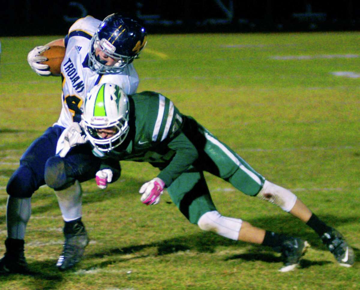 The Green Wave's Kyler Cyr uses every bit of leverage he can muster to shove a tough Trojan ballcarrier out of bounds during New Milford High School football's 34-20 defeat to Weston, Nov. 14, 2014 at NMHS.during New Milford High School football's 34-20 defeat to Weston, Nov. 14, 2014 at NMHS.