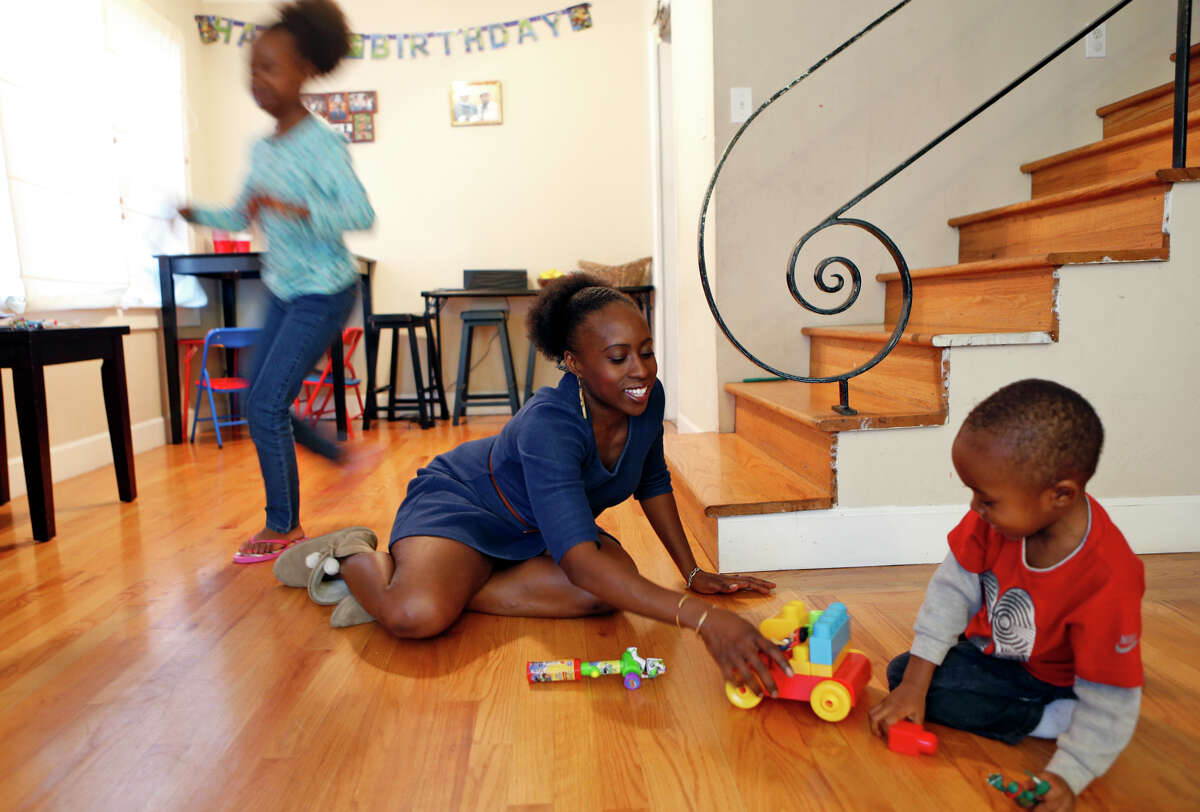Kehinde Kujichagulia-Seitu plays with her son, Cameron, 3, as her daughter, Xion, 10, runs past at their Oakland home.