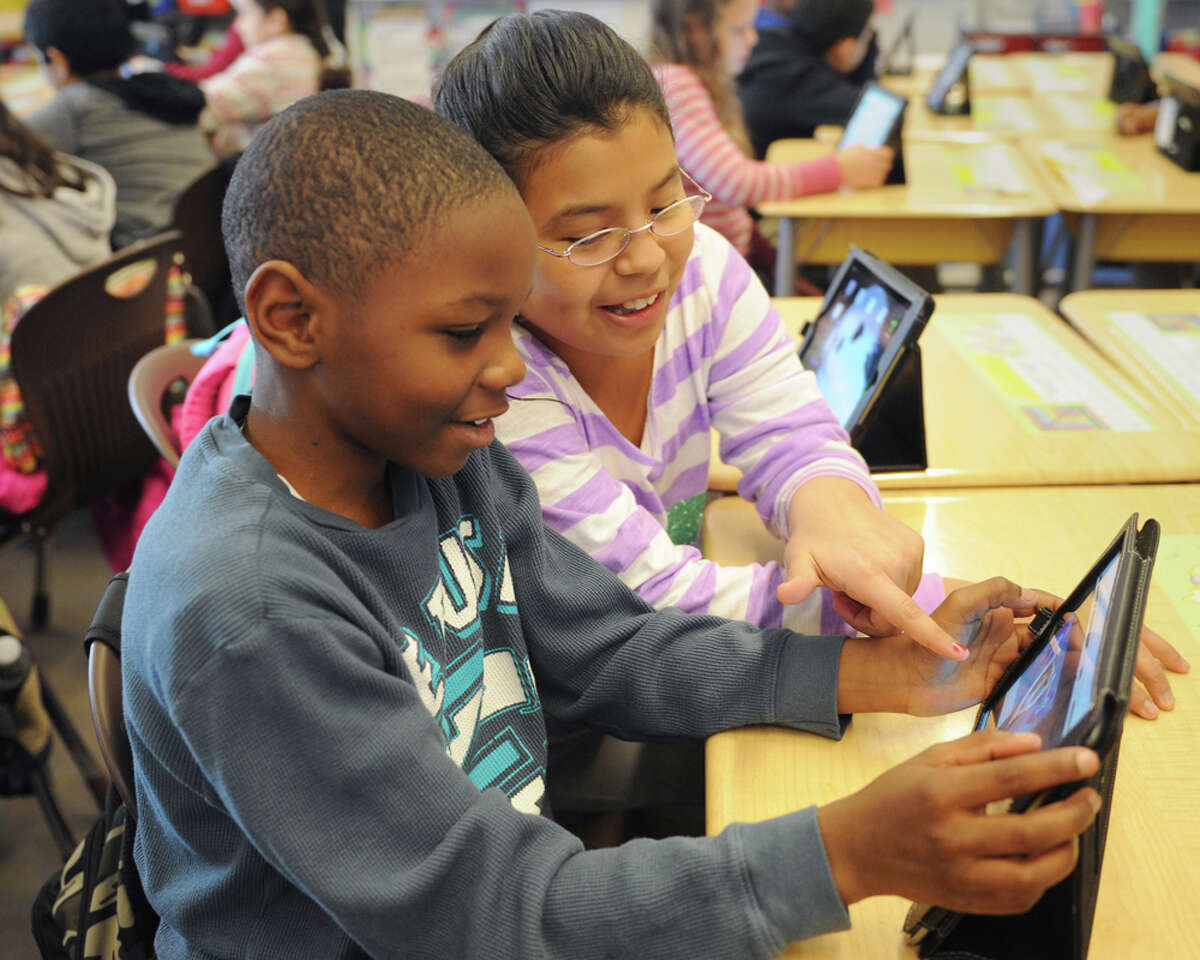 Fifth-graders Jaden Dorsey and Aileen Cebanos use iPads to participate in the Global Read Aloud initiative at Hamilton Avenue School in Greenwich, Conn. Thursday, Dec. 4, 2014. The initiative is like a digital book club in which students from schools across the country and world discuss books they read through an online forum. The iPad program allows students to post comments and respond to questions and polls asked by the teachers.
