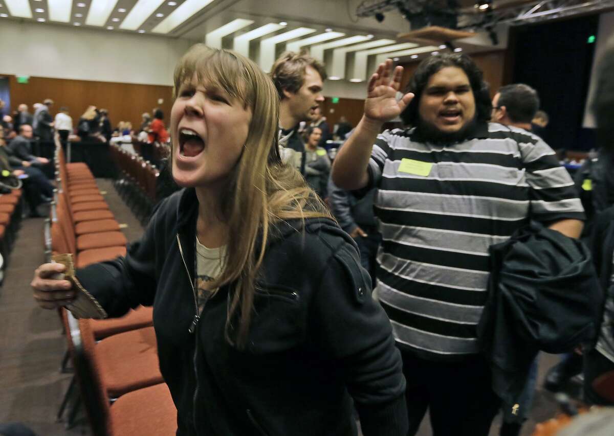 CORRECTS SPELLING OF LAST NAME TO ITNYRE INSTEAD OF ITAYRE- Amelia Itnyre, 23, and Sebastian Cano, 21, students at University of California Davis, react after the vote to raise tuition fees was announced during the UC Regents meeting in San Francisco, Thursday, Nov. 20, 2014. The Regents approved raising tuition by as much as 5 percent in each of the next five years unless the state devotes more money to the 10-campus system. (AP Photo/Eric Risberg)