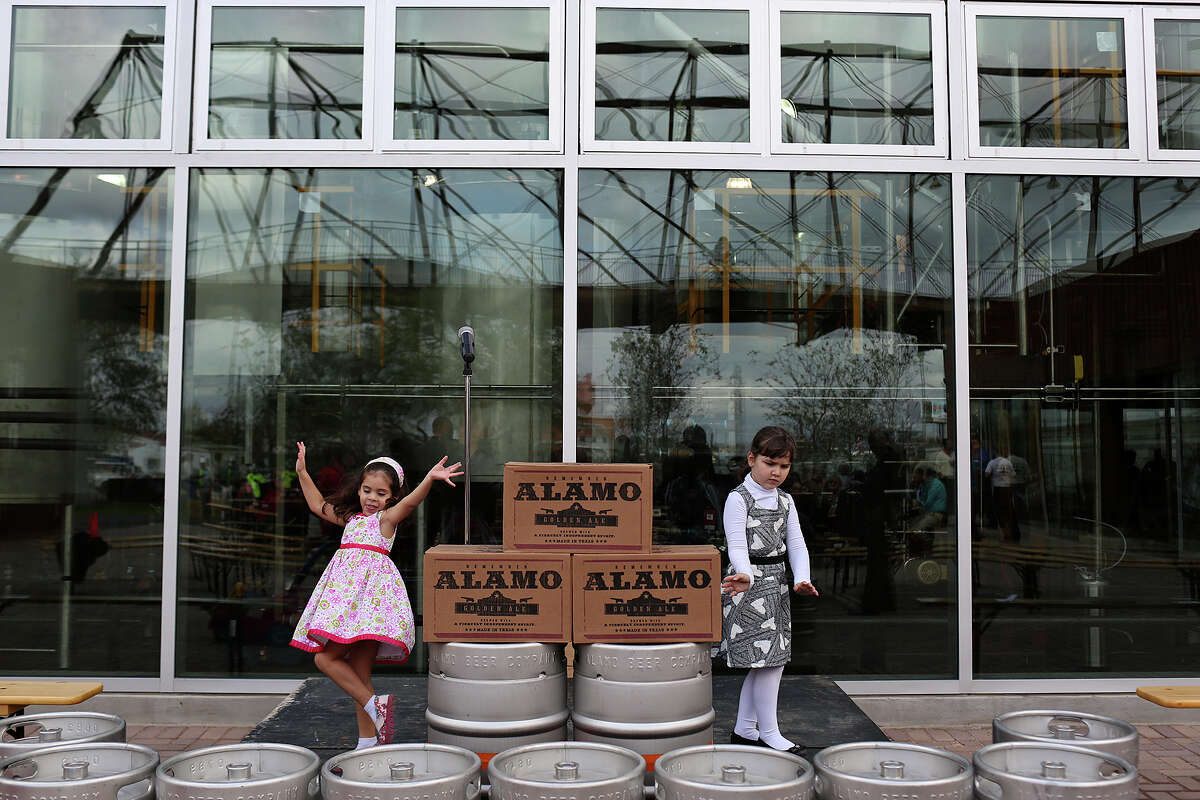 Vania Sovero, 3, left, and Georgia Simor, 5, the daughter of Alamo Brewing Company President Eugene Simor, entertain themselves by dancing on the stage after the ribbon cutting for Alamo Brewing Company in San Antonio on Friday, Dec. 5, 2014.