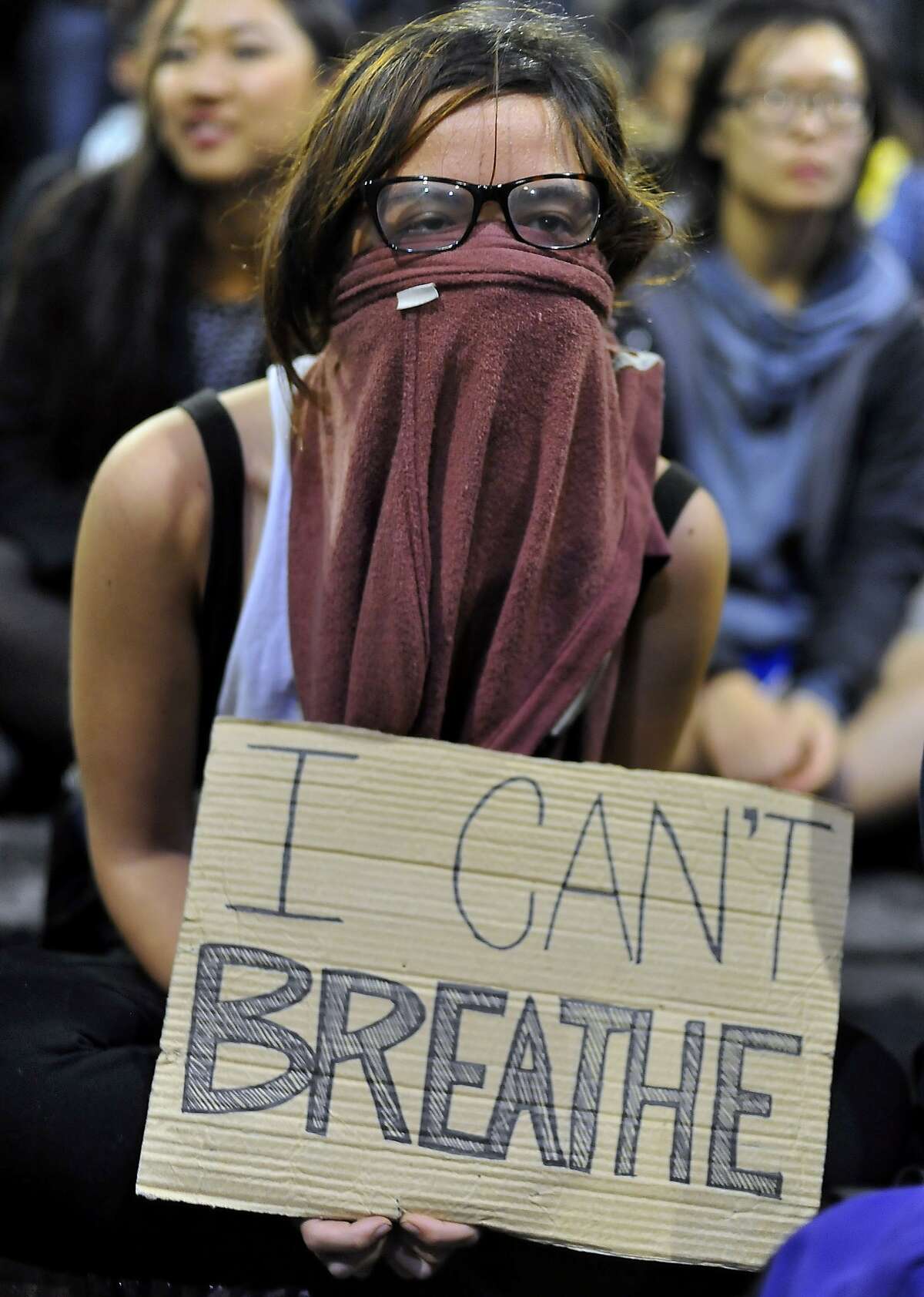 A girl who declined to give her name holds a sign in front of a police skirmish line during demonstrations in Berkeley, California on Saturday, December 6, 2014. Protesting continued through the night in response to the grand jury verdicts in the shooting death of Michael Brown in Ferguson, Missouri and the chokehold death of Eric Garner in New York City.