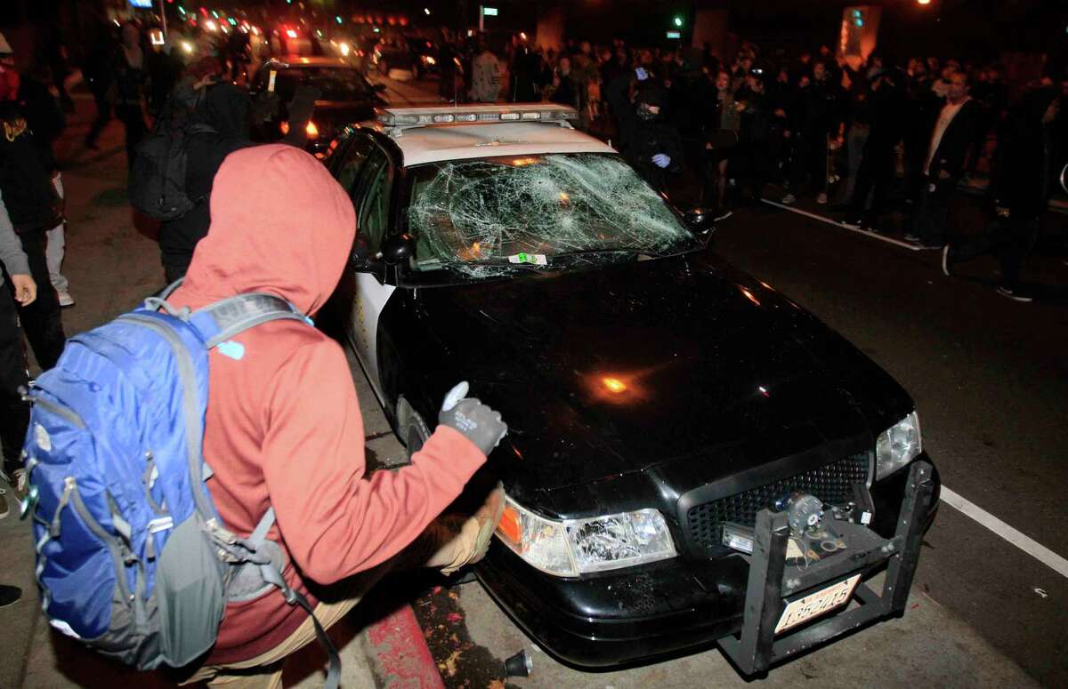 A demonstrator kicks a police car during a protest in Berkeley, Calif. Sunday, December 7, 2014 shining light on the chokehold death of Eric Garner in New York City and the shooting of Mike Brown in Ferguson, Missouri.