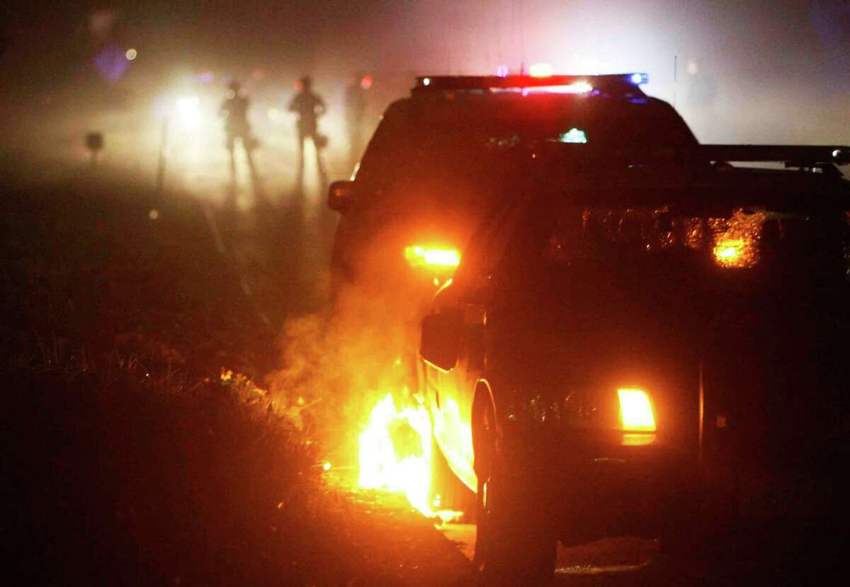Demonstrators set a small fire near a police car on the Highway 24 on ramp at 52nd and Shattuck Avenue during a protest in Berkeley, Calif. Sunday, December 7, 2014 shining light on the chokehold death of Eric Garner in New York City and the shooting of Mike Brown in Ferguson, Missouri.