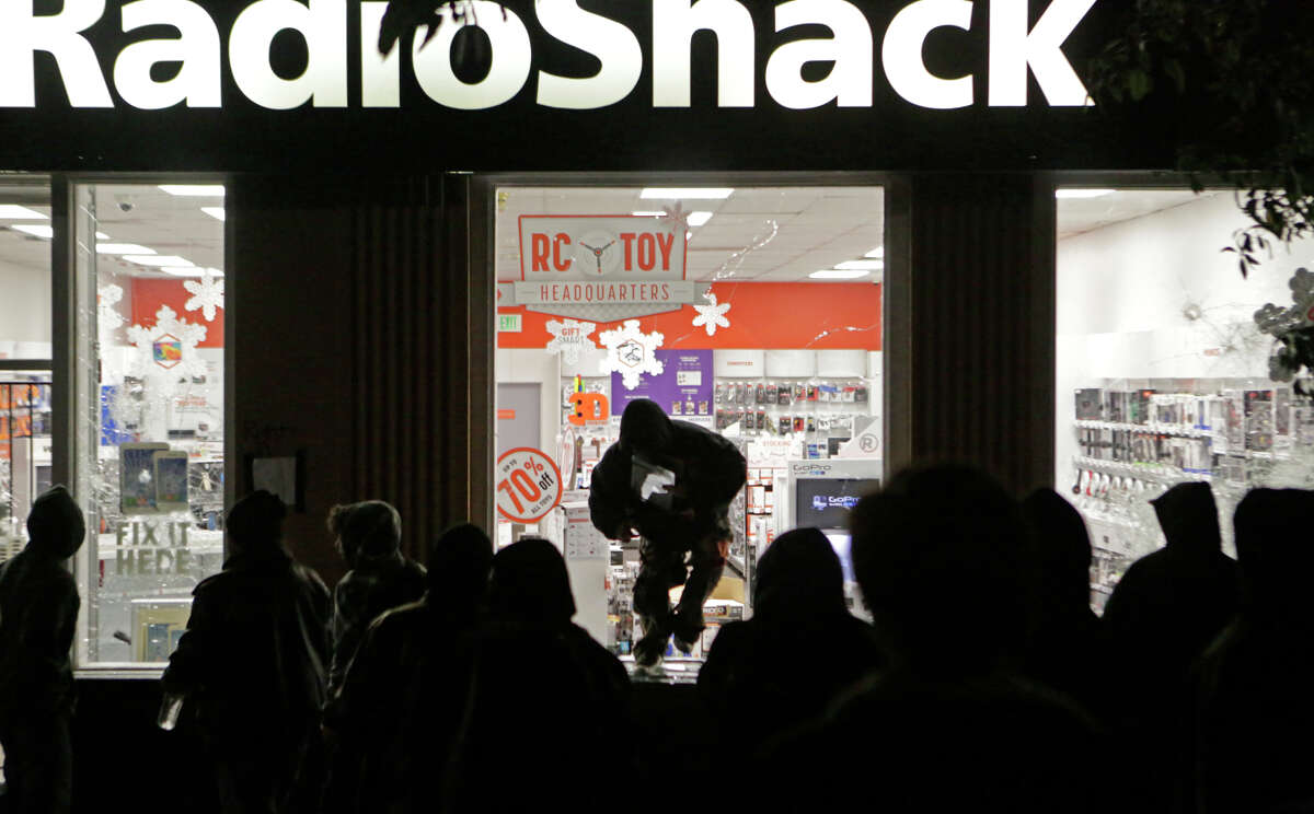 A looter leaps out of a Radio Shack on Shattuck Avenue in Berkeley after protests against police killings of unarmed black men in Missouri and New York spiraled into vandalism.