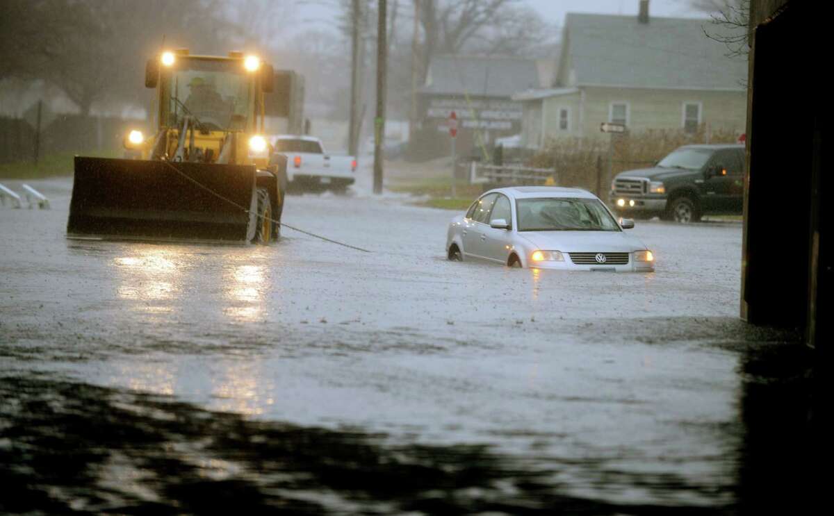 A sedan is towed out of a flooded Surf Avenue near the I-95 overpass in Stratford, Conn., Tuesday, Dec. 9, 2014.