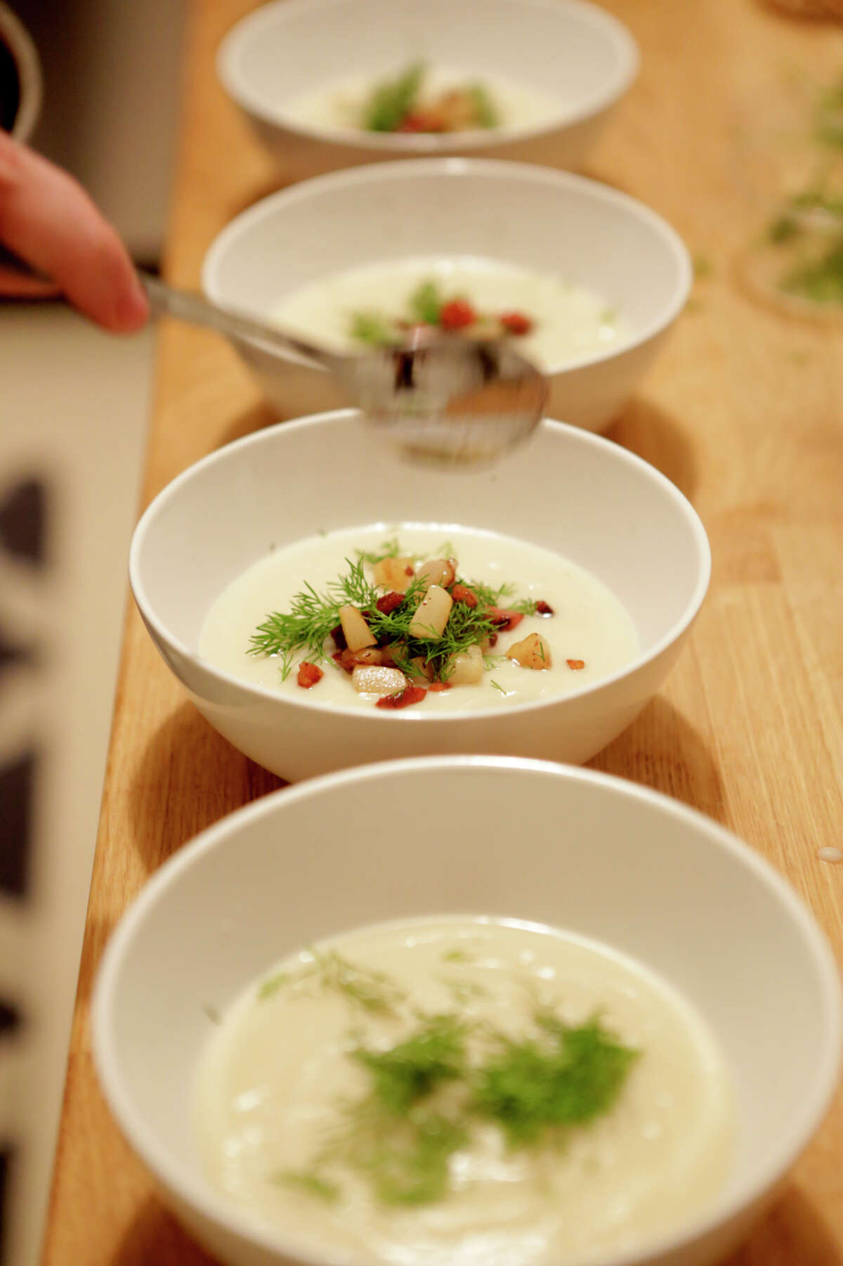 The soup is garnished with pears, bacon and dill before serving.