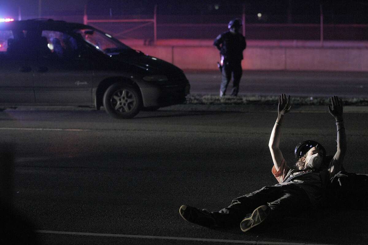 A masked demonstrator lies down in the lanes of Highway 24 near the 580 interchange as protesters briefly occupy the highway, in Berkeley, California, on Tuesday, Dec. 9, 2014. Demonstrators are protesting grand jury decisions in the shooting death of Michael Brown in Ferguson, Missouri and chokehold death of Eric Garner in New York City.