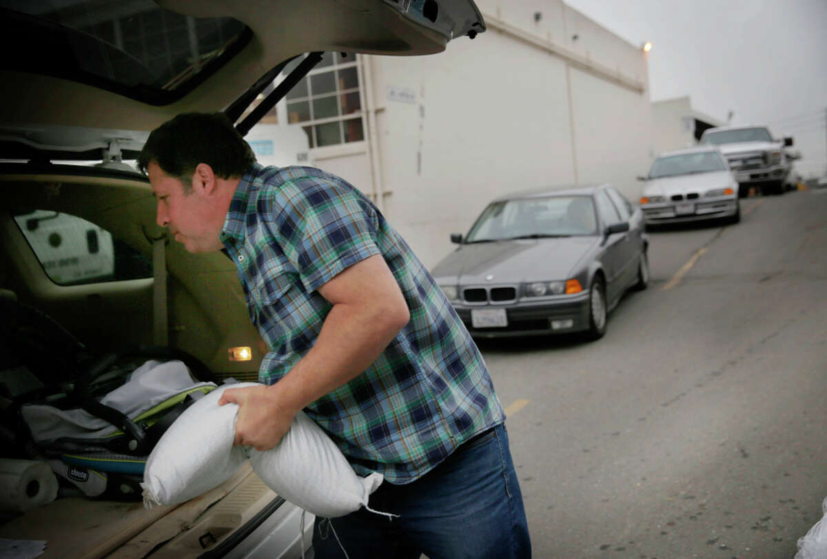 Gregory Gamp of San Francisco loads a sandbag into his car as other drivers wait in line. Gamp had to wait about two hours.