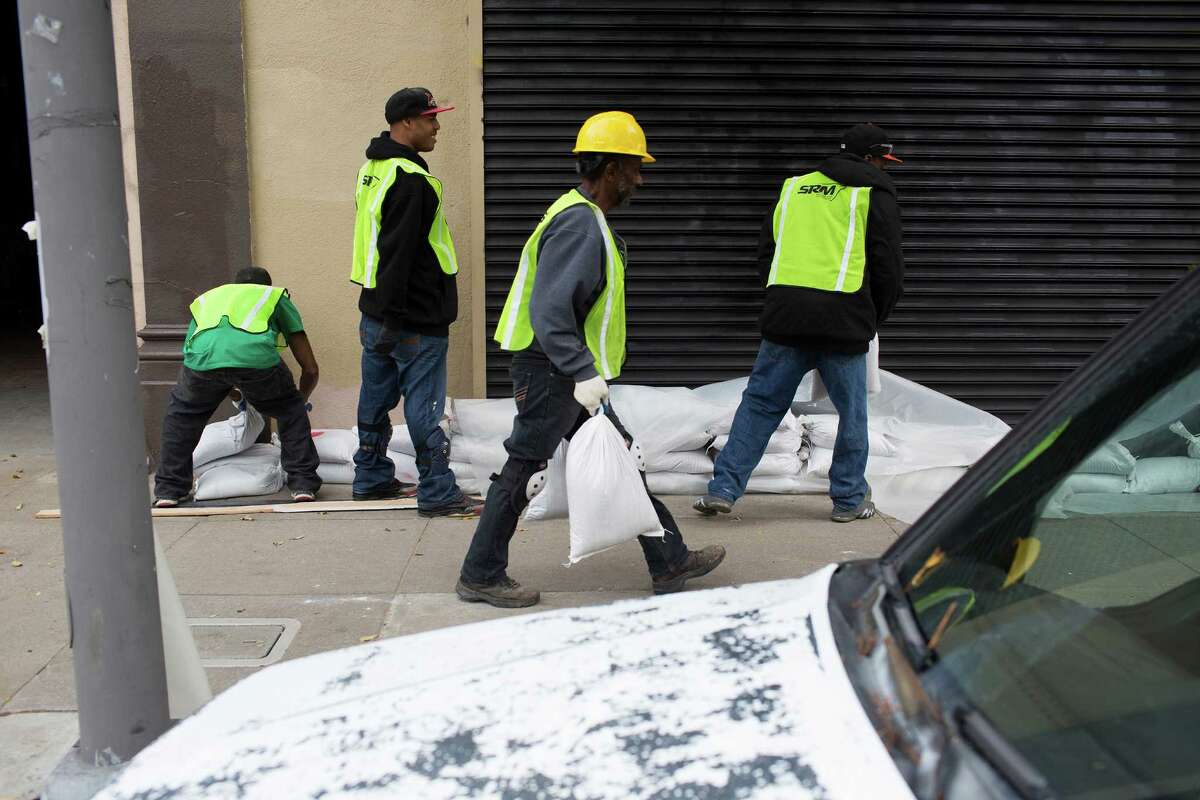 Workers with ServiceMasters Recovery Management sandbag open spaces at Hilde-Brand Furniture Inc. on Folsom St. in San Francisco, Calif. on Wednesday, December 10, 2014. The properties in the area were damaged by floods in a relatively light storm last week and residents and businesses braced for Thursday's storm.