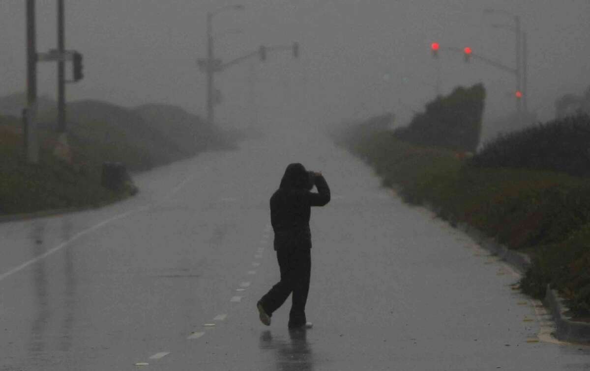 FILE PHOTO: A person walks across Great Highway which was closed due to risk of high flooding and strong winds near Ocean Beach in San Francisco, Calif. Thursday, December 11, 2014 during the biggest storm to hit the Bay Area in 6 years