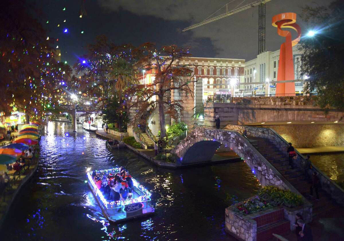 A barge, decorated for Christmas and carrying the Southside High School choir, cruises on the San Antonio River on Thursday, Dec. 11, 2014.