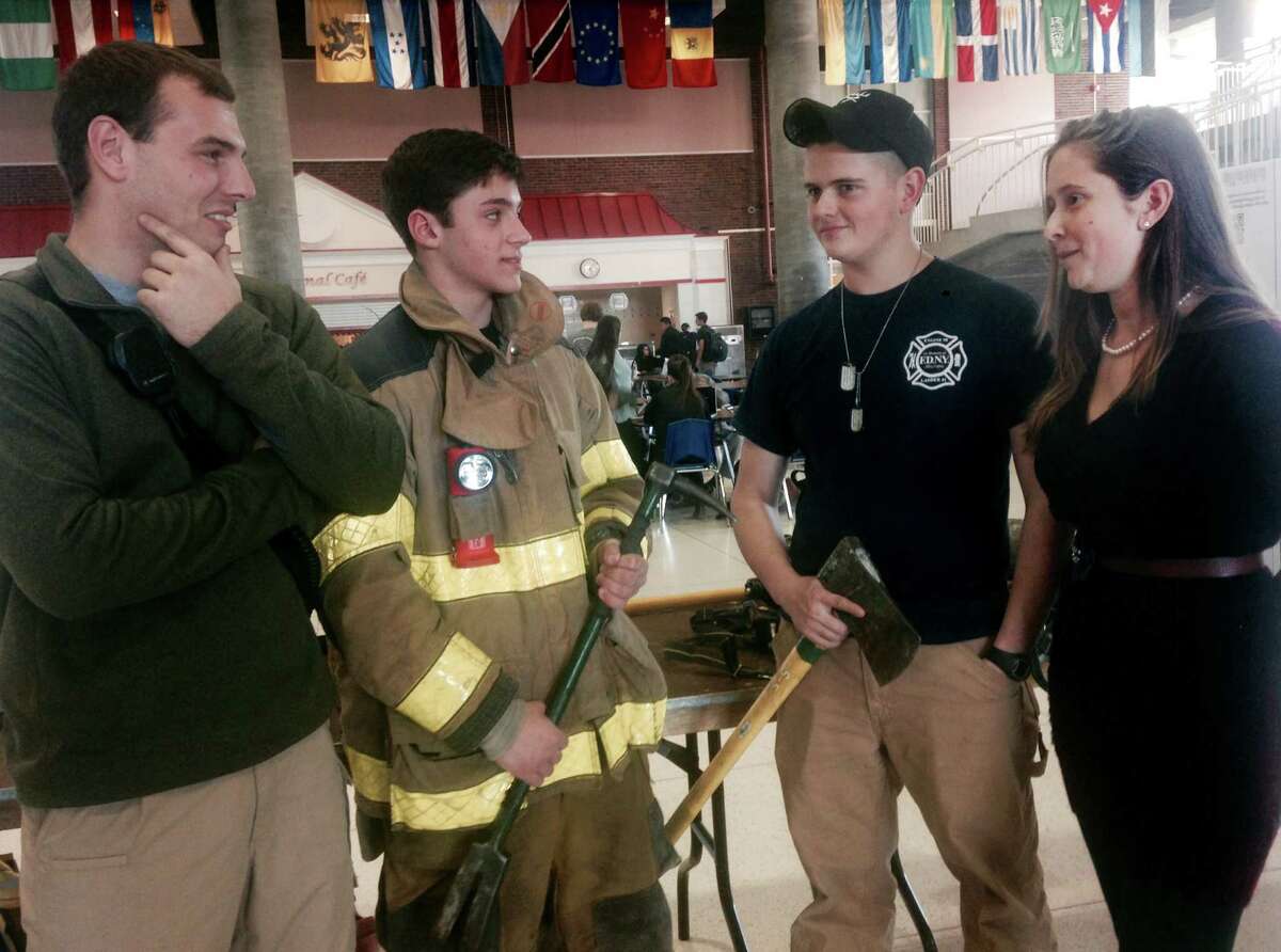 From left, Nicholas Chiappetta, a Sound Beach volunteer firefighter, talks with Greenwich High students and fire explorers Nicholas Cesarini, James DeFazio and Sara DeFazio on Friday in the Greenwich High student center during Be Safe Day on Friday, Dec. 12, 2014.